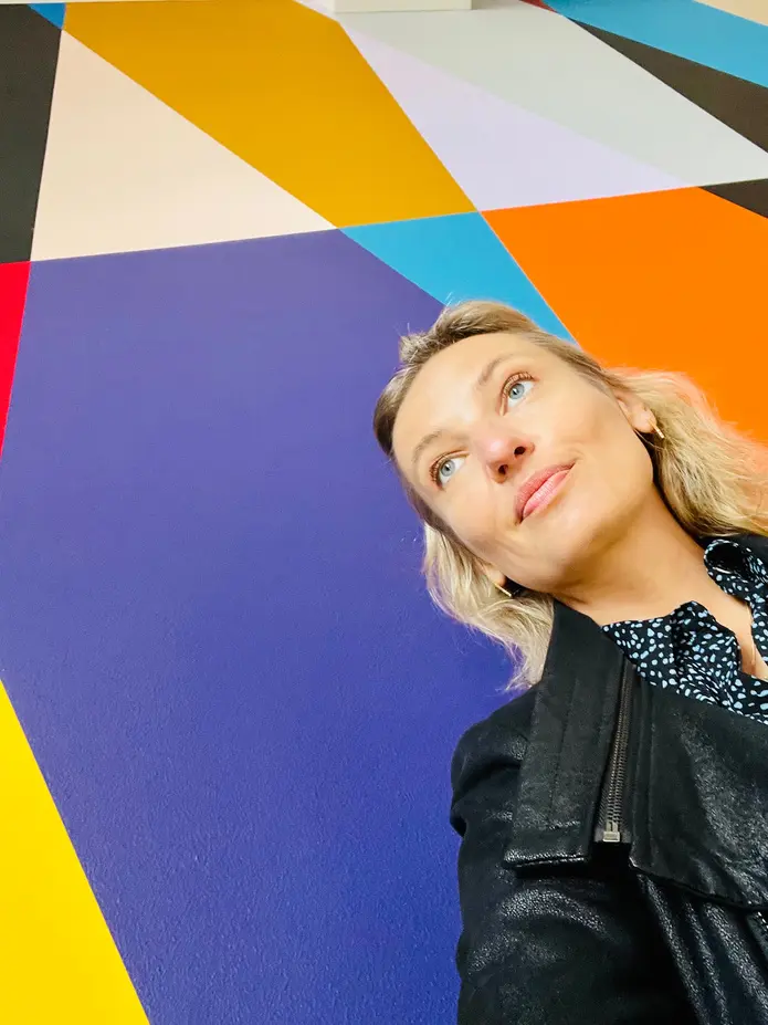 Portrait of Elise against a colourful geometric ceiling